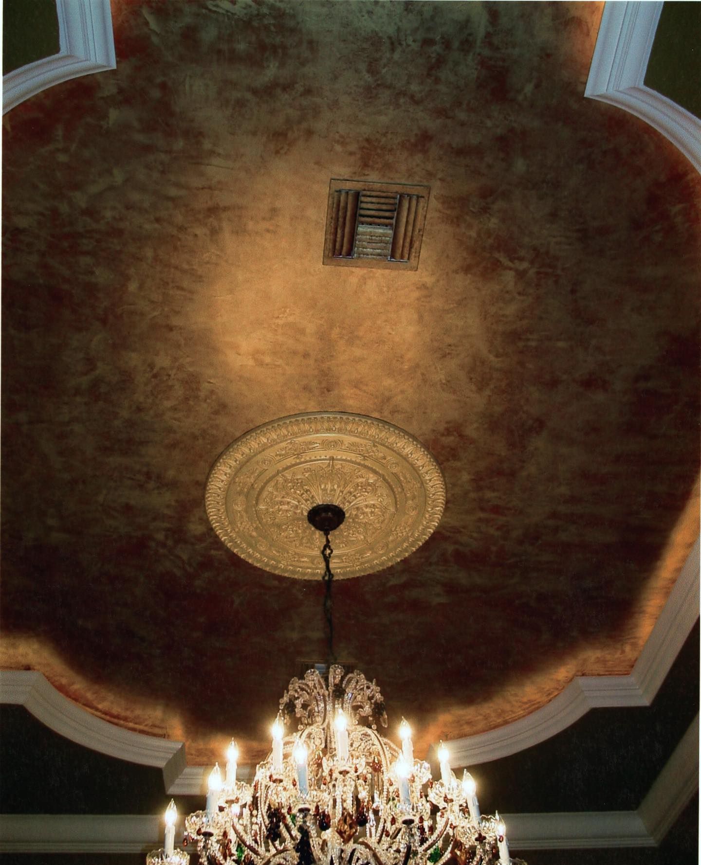 Ornate gold-painted ceiling with chandelier and decorative molding.