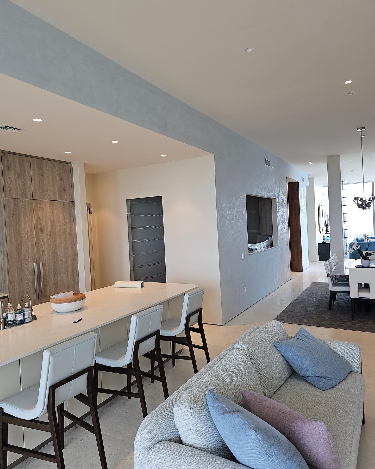 Modern kitchen and living area with light blue walls, a long island, and a gray sofa.