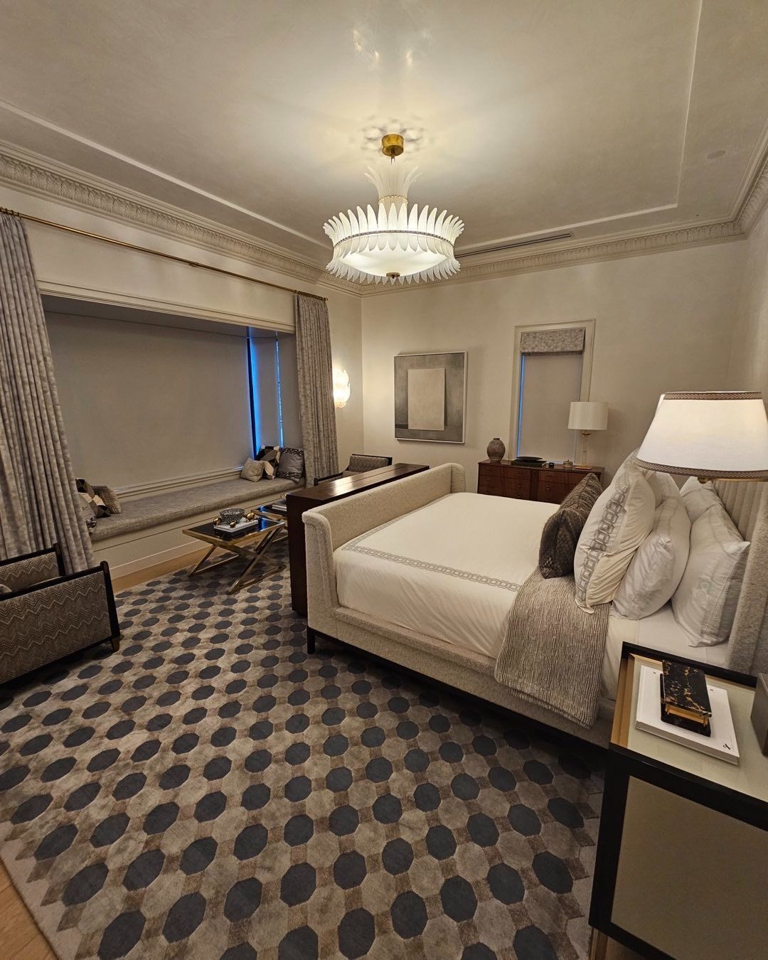 Luxurious bedroom with a bed, patterned rug, and ornate chandelier.