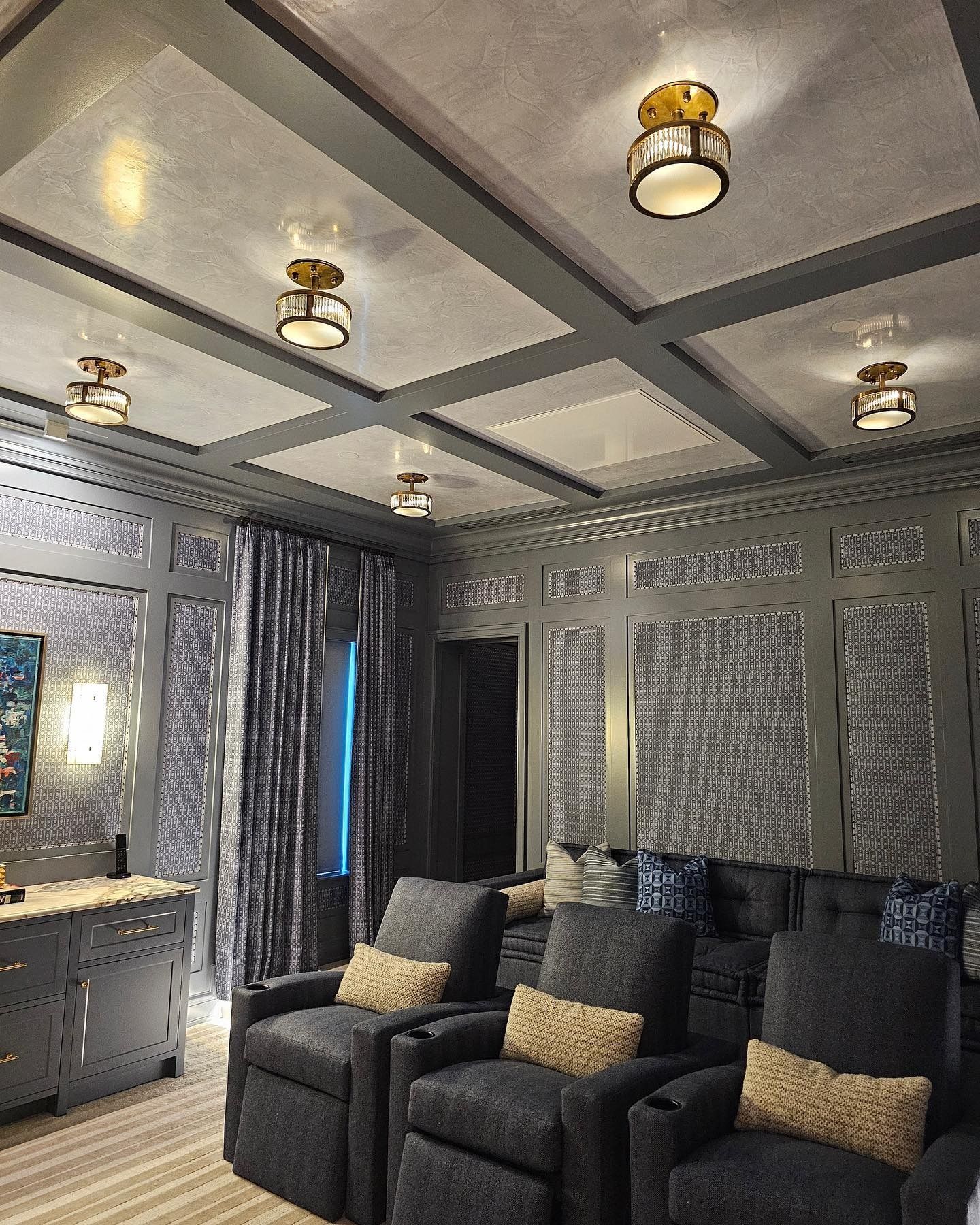 Gray home theater with recessed lighting, paneled walls, and plush seating.