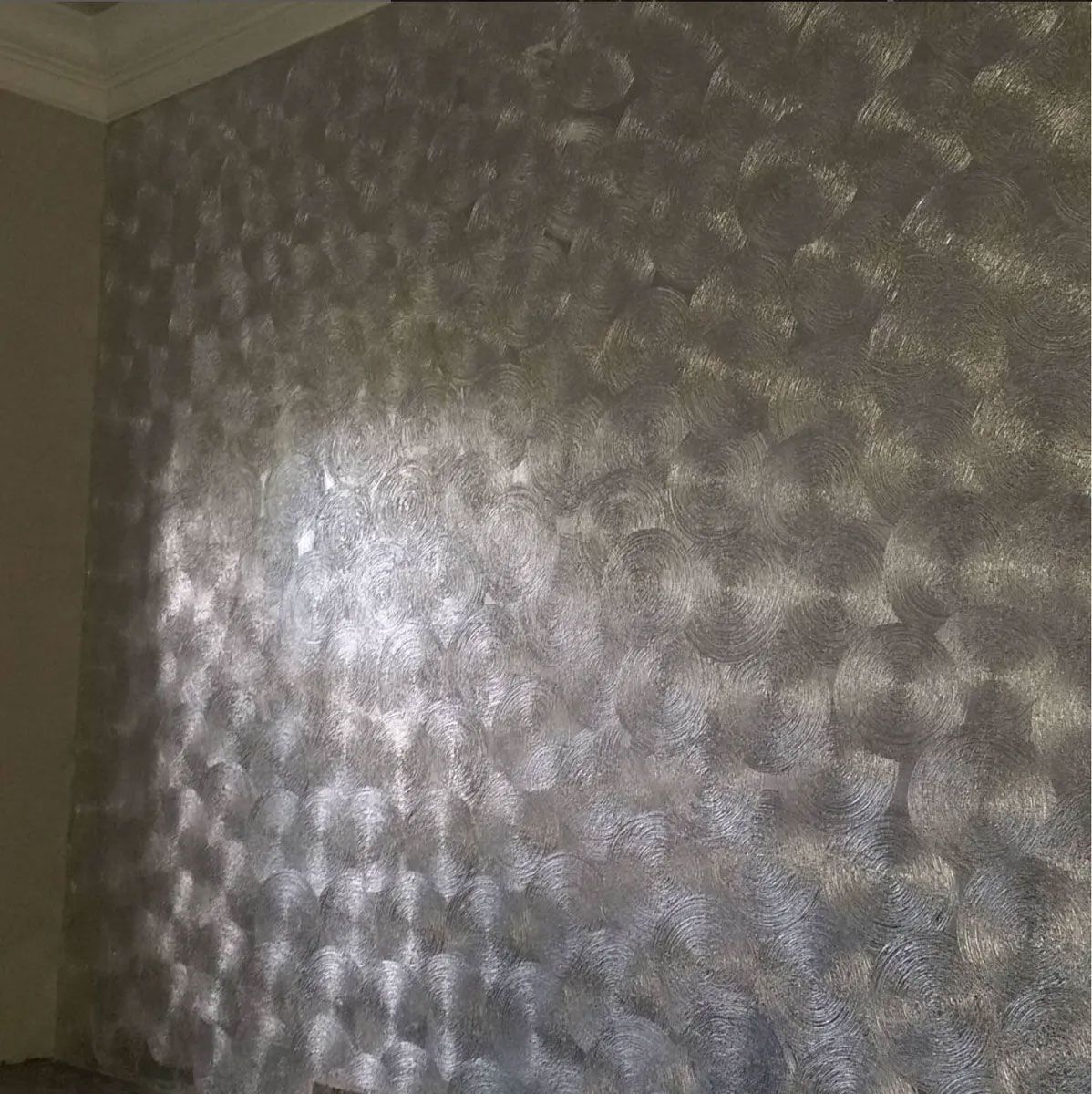 Textured silver wall with a geometric pattern, likely paint, in a room.