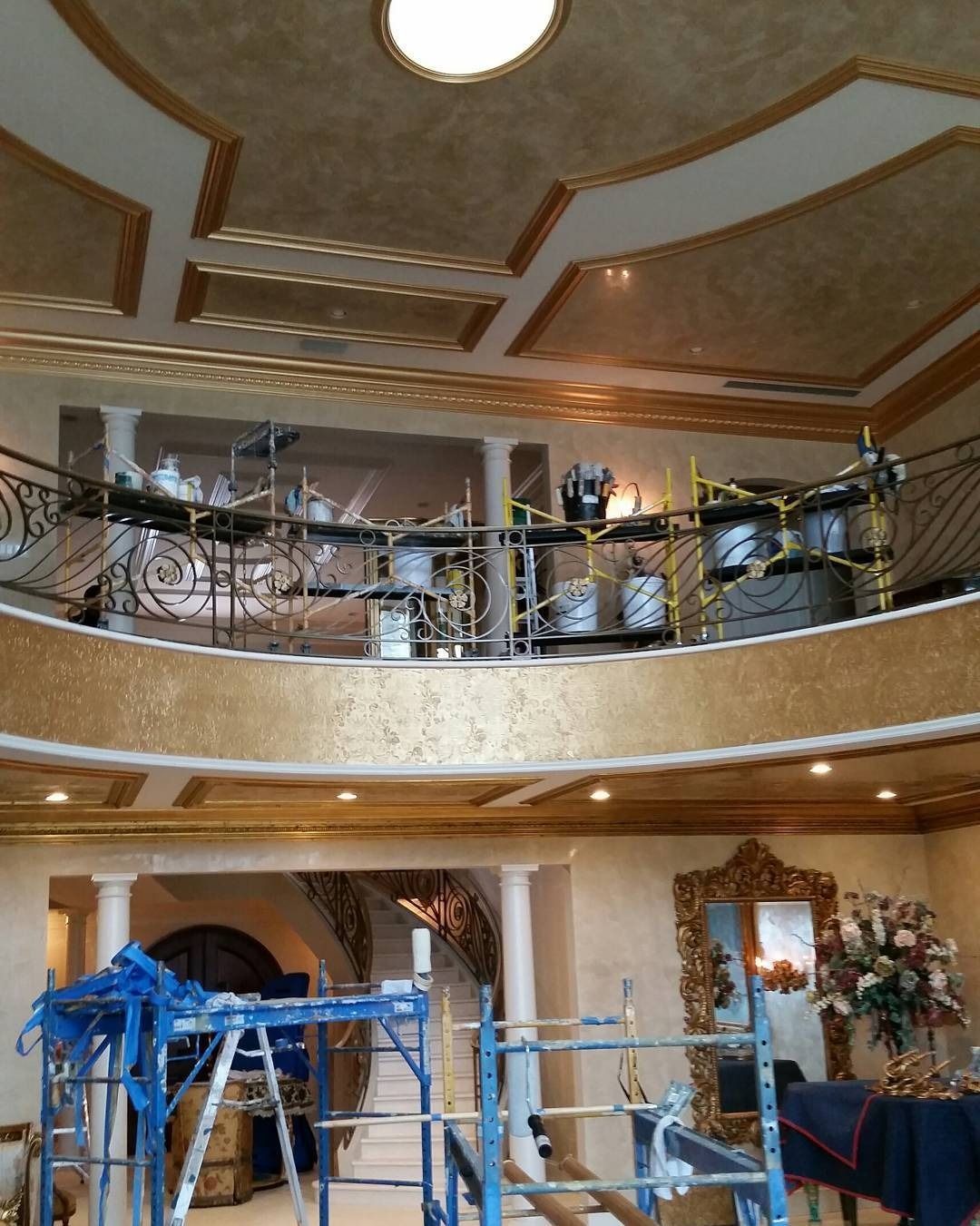 A luxurious interior with ornate gold-trimmed walls and ceiling. A drum set is set up on a balcony.