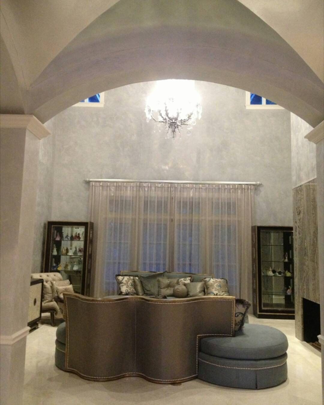 Elegant living room with arched ceiling, crystal chandelier, and stylish seating.