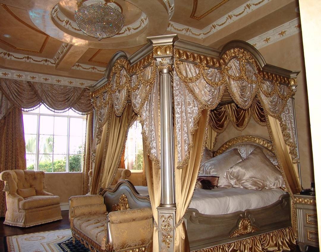 Ornate bedroom with a golden canopy bed, detailed ceiling, and a window.