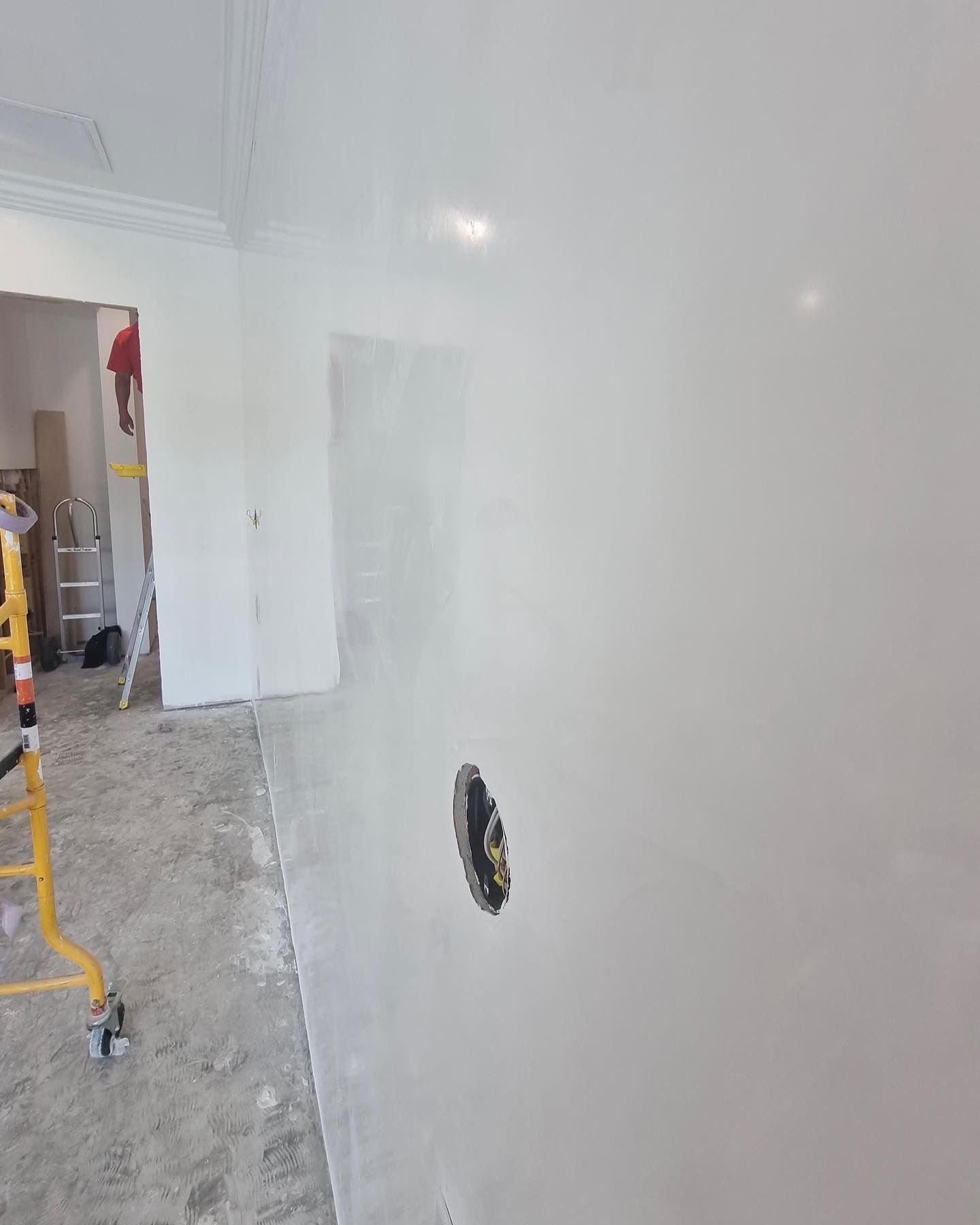 White wall with an electrical outlet, under construction. A partially completed room.