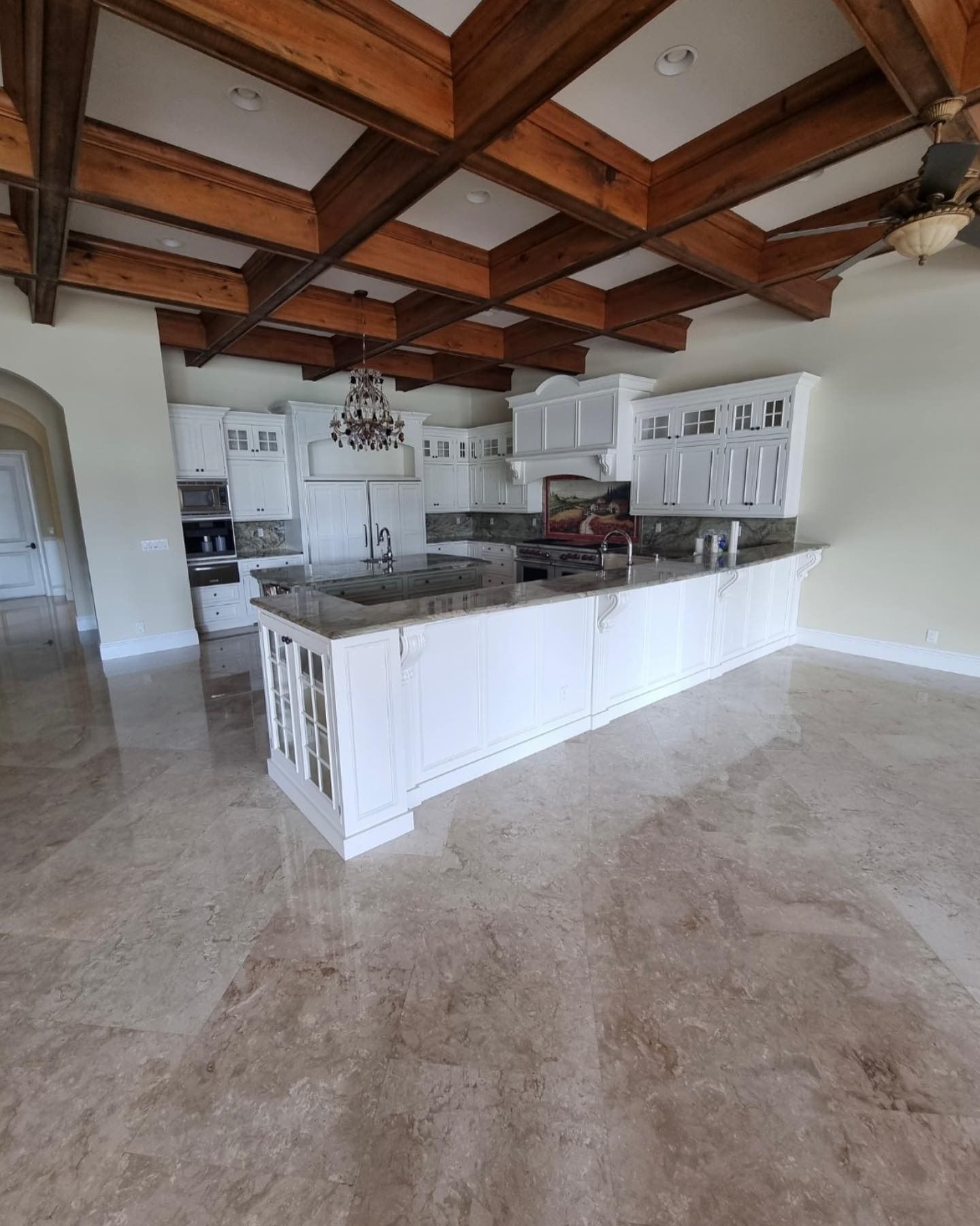 Spacious kitchen with white cabinets, granite countertops, and wooden beams on the ceiling.
