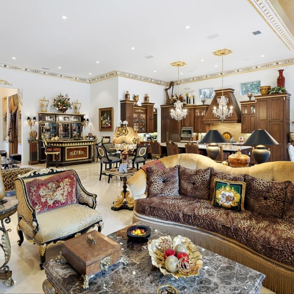 Luxurious living room with ornate furniture, gold accents, and open kitchen.