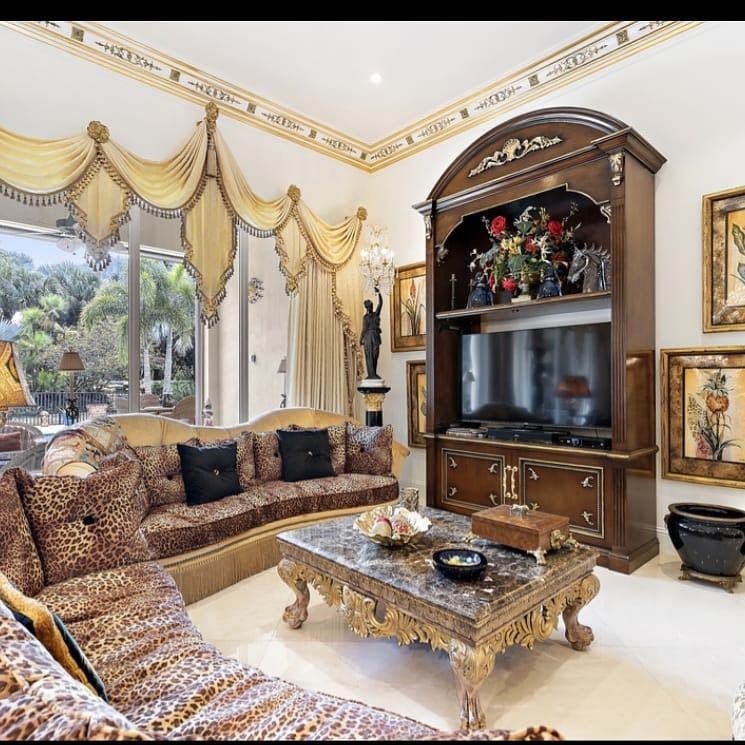 Living room with leopard-print couch, ornate furniture, large TV, and decorated ceiling.
