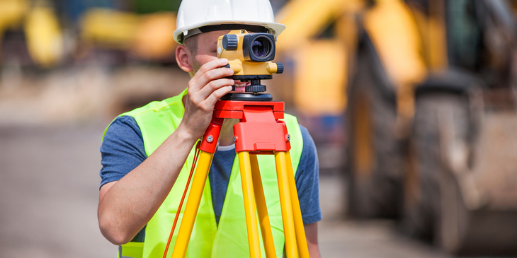 a construction worker is using a level on a tripod .