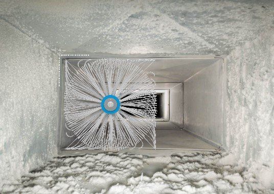 An HVAC technician cleaning a dryer vent using a spinning brush to remove built-up lint and debris.