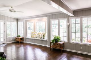 A living room with a window seat and lots of windows.