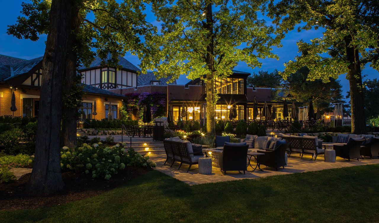 A patio area with furniture and trees is lit up at night.