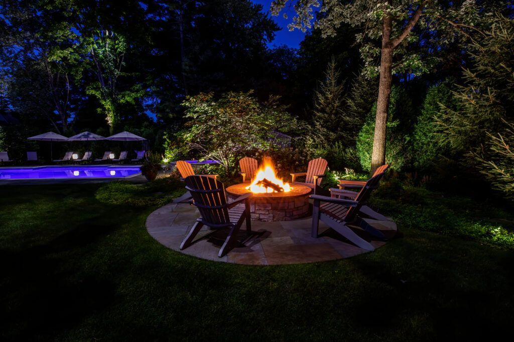 A fire pit with chairs around it in a backyard at night.