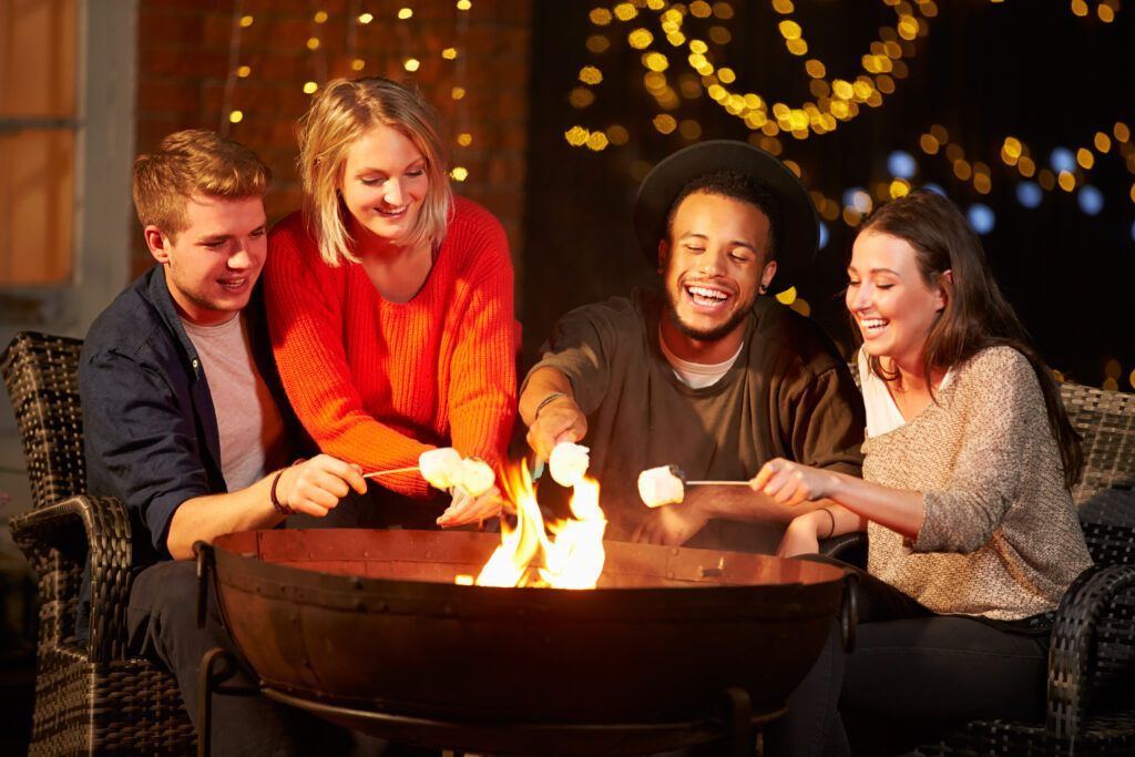 A group of people are roasting marshmallows over a fire pit.