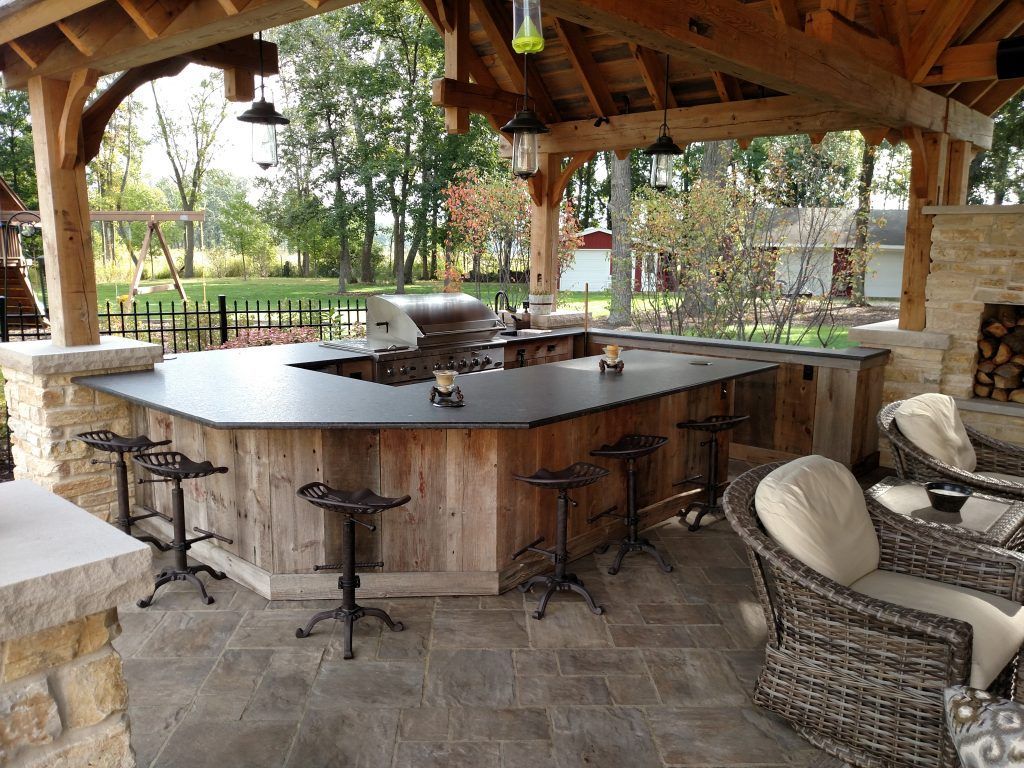 A patio area with a large wooden bar and wicker chairs.