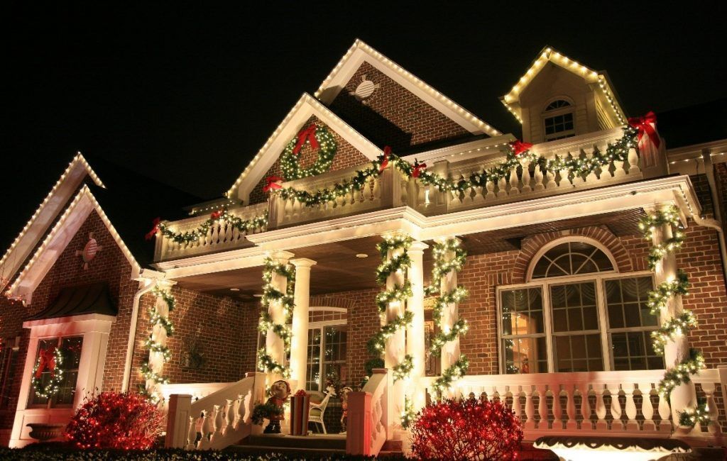 A large brick house decorated for christmas at night