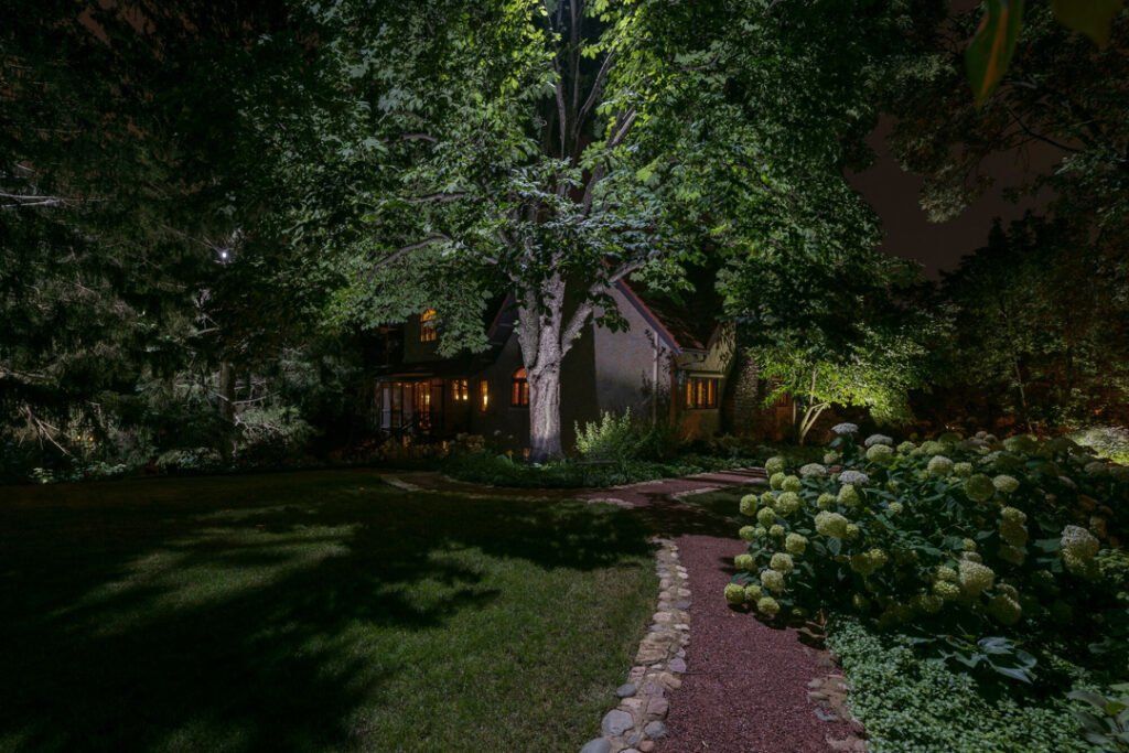 A path leading to a house is lit up at night.