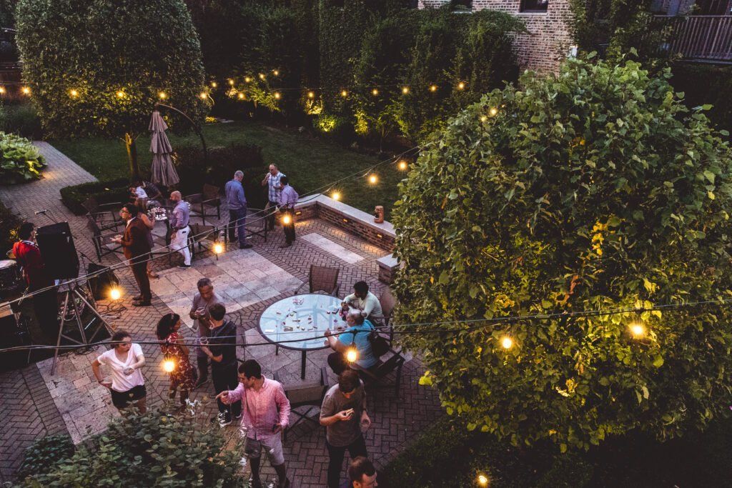 A group of people are standing around a table in a garden at night.