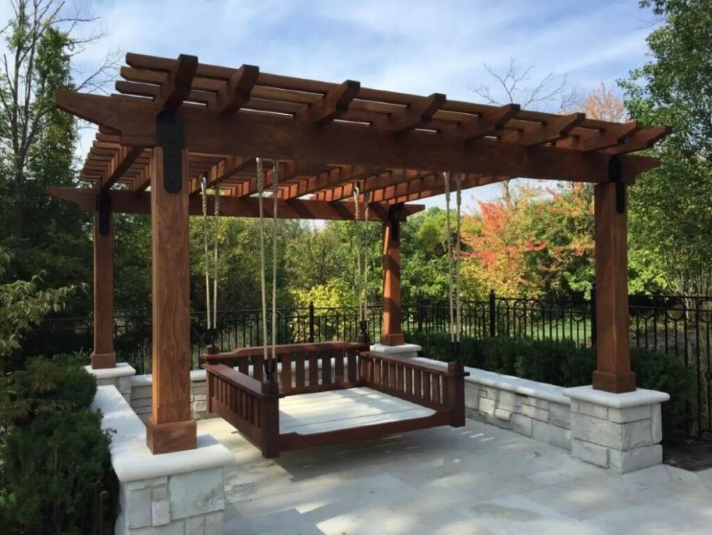 A wooden pergola with a swing underneath it