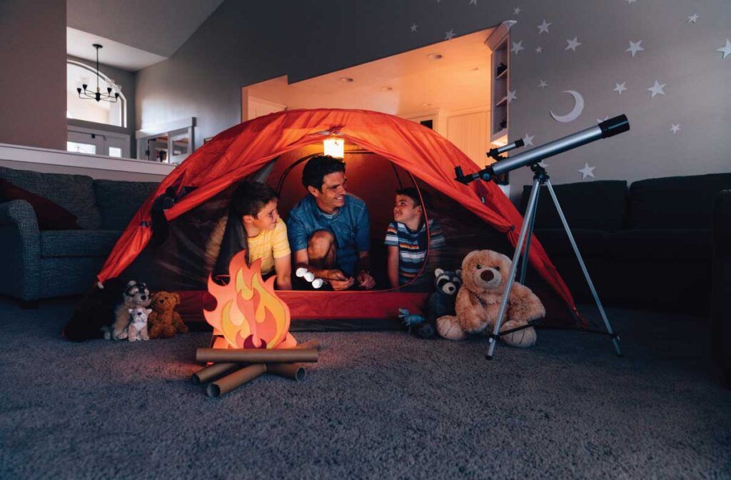 A family is sitting in a tent in a living room.