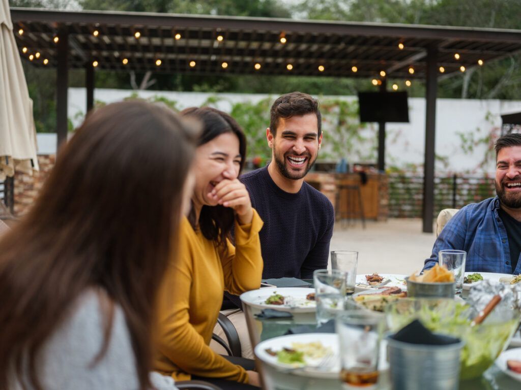 A group of people are sitting at a table eating food and laughing.