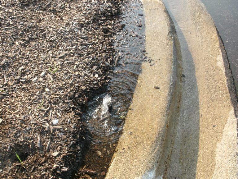 A concrete curb with water coming out of it