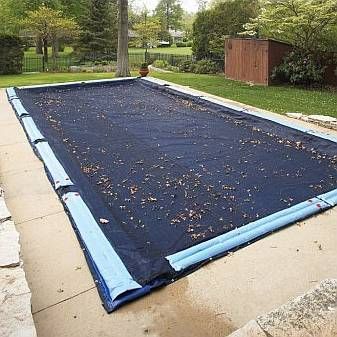 A large swimming pool with a blue cover on it.