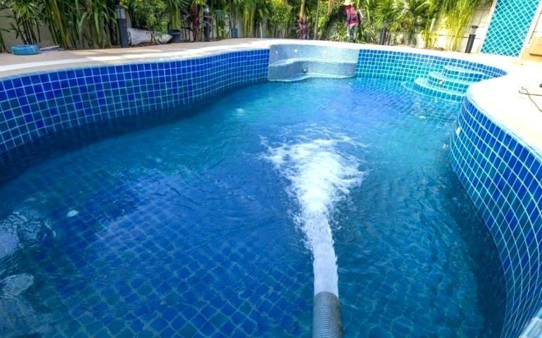 A swimming pool with blue tiles and a hose coming out of it.