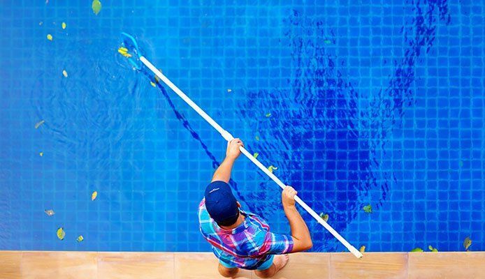 A man is cleaning a swimming pool with a net.