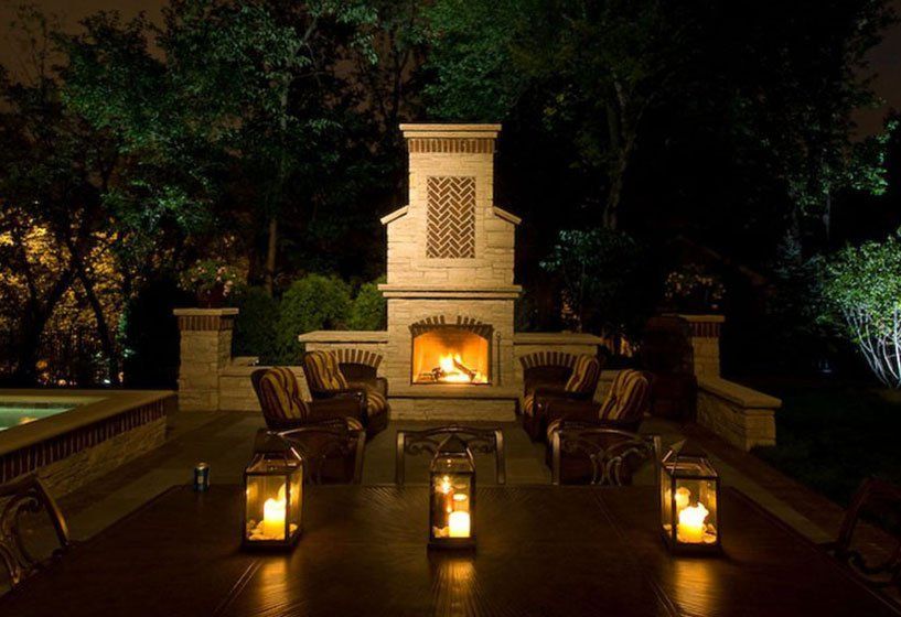 A patio with a fireplace and lanterns at night