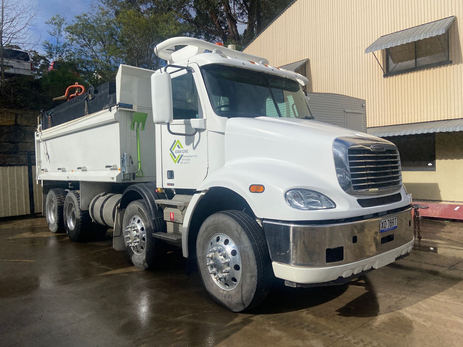 A white dump truck is parked in front of a building. — Adam Lowe Earthmoving Pty Ltd in Somersby, NSW