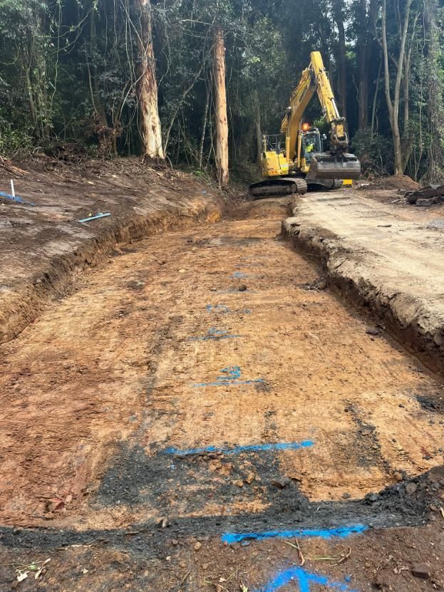 A Yellow Excavator is Digging a Hole in the Dirt — Adam Lowe Earthmoving Pty Ltd in Somersby, NSW