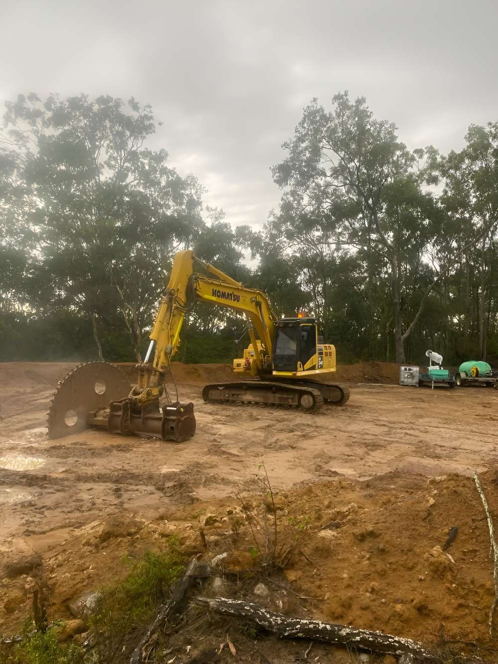 A Yellow Excavator Is Sitting on Top of A Dirt Field — Adam Lowe Earthmoving Pty Ltd in Somersby, NSW