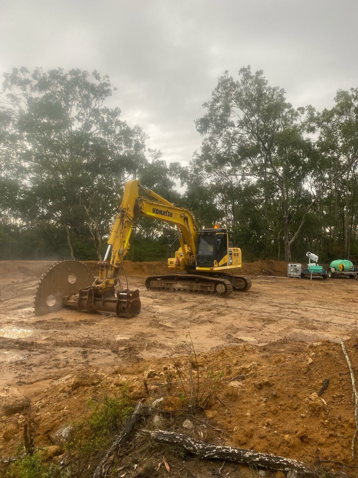 A yellow excavator is driving through a dirt field. — Adam Lowe Earthmoving Pty Ltd in Somersby, NSW