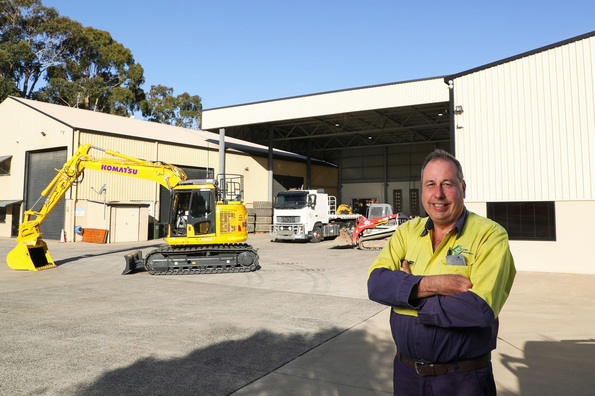 A man wearing Adam Lowe Earthmoving uniform in front of their machinery shed — Adam Lowe Earthmoving Pty Ltd in Somersby, NSW