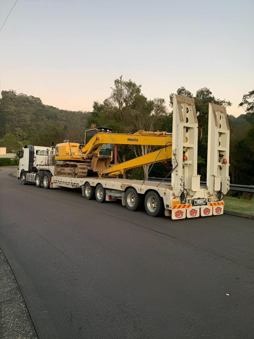 A Truck Is Carrying a Yellow Excavator on A Trailer — Adam Lowe Earthmoving Pty Ltd in Somersby, NSW