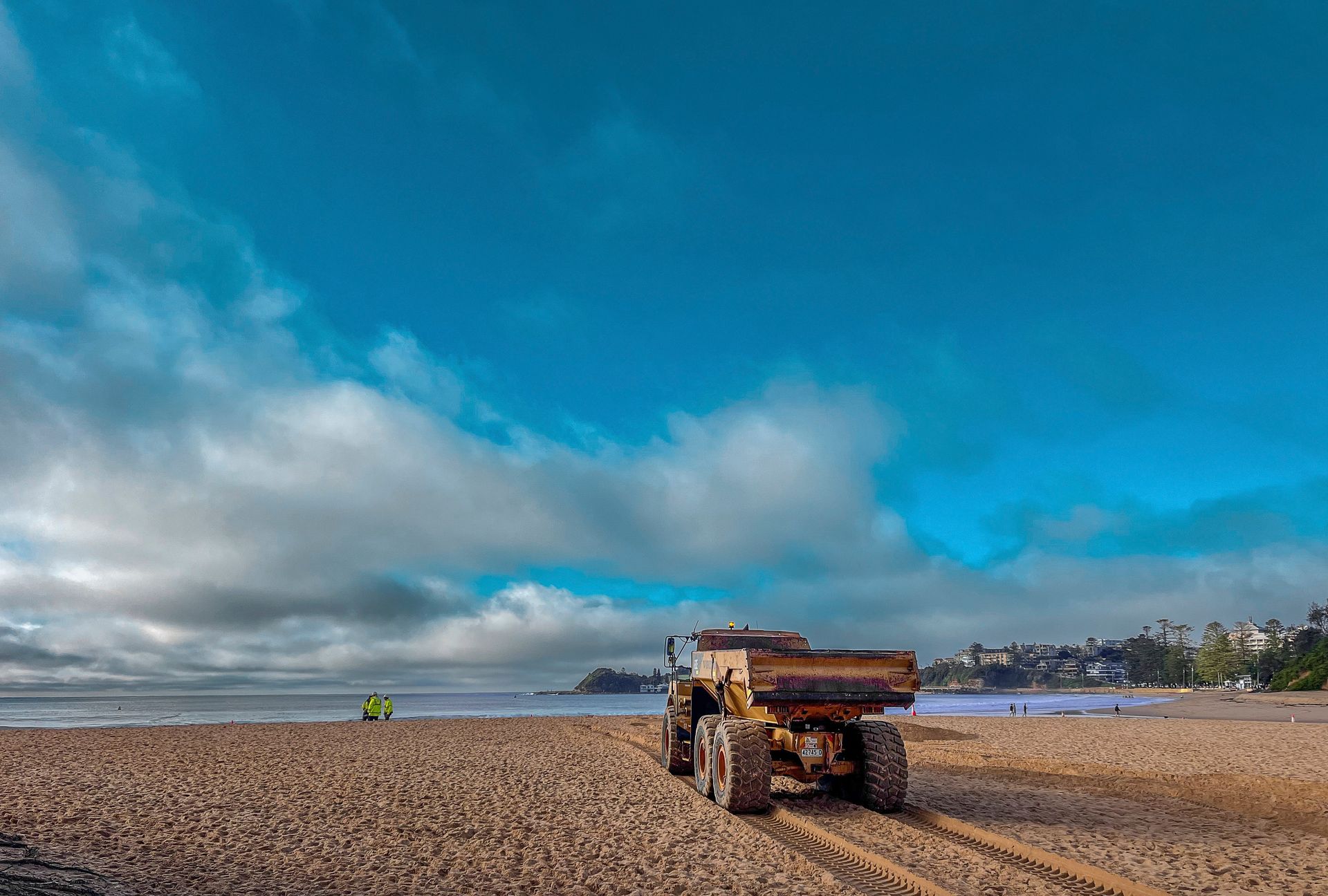 A dump truck is driving down a dirt road on a beach. — Adam Lowe Earthmoving Pty Ltd in Somersby, NSW