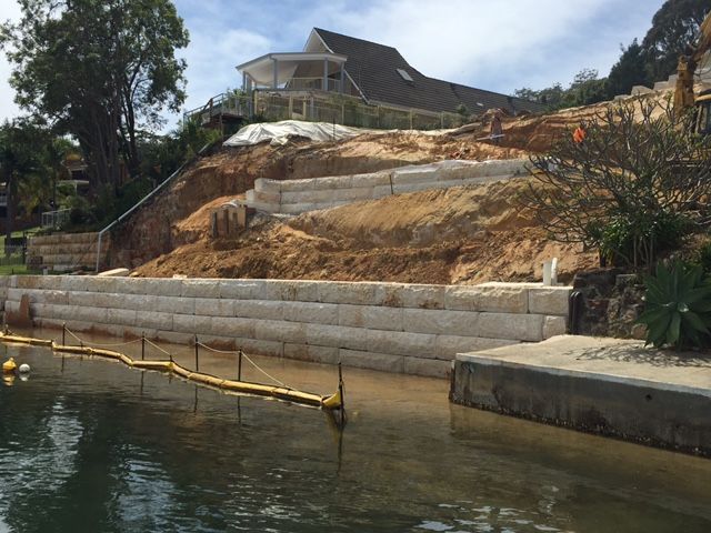 A house is being built on a hill next to a body of water. — Adam Lowe Earthmoving Pty Ltd in Somersby, NSW