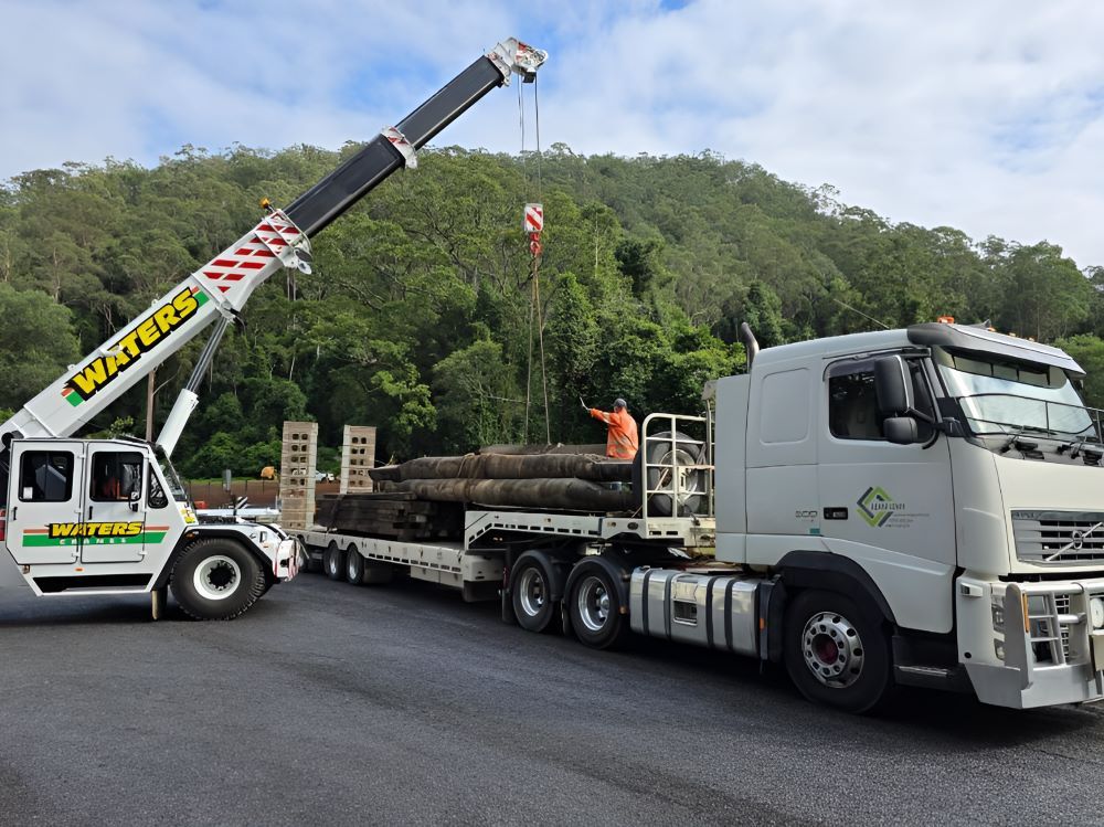 A Truck with A Crane Attached to It Is Carrying Logs — Adam Lowe Earthmoving Pty Ltd in Somersby, NSW