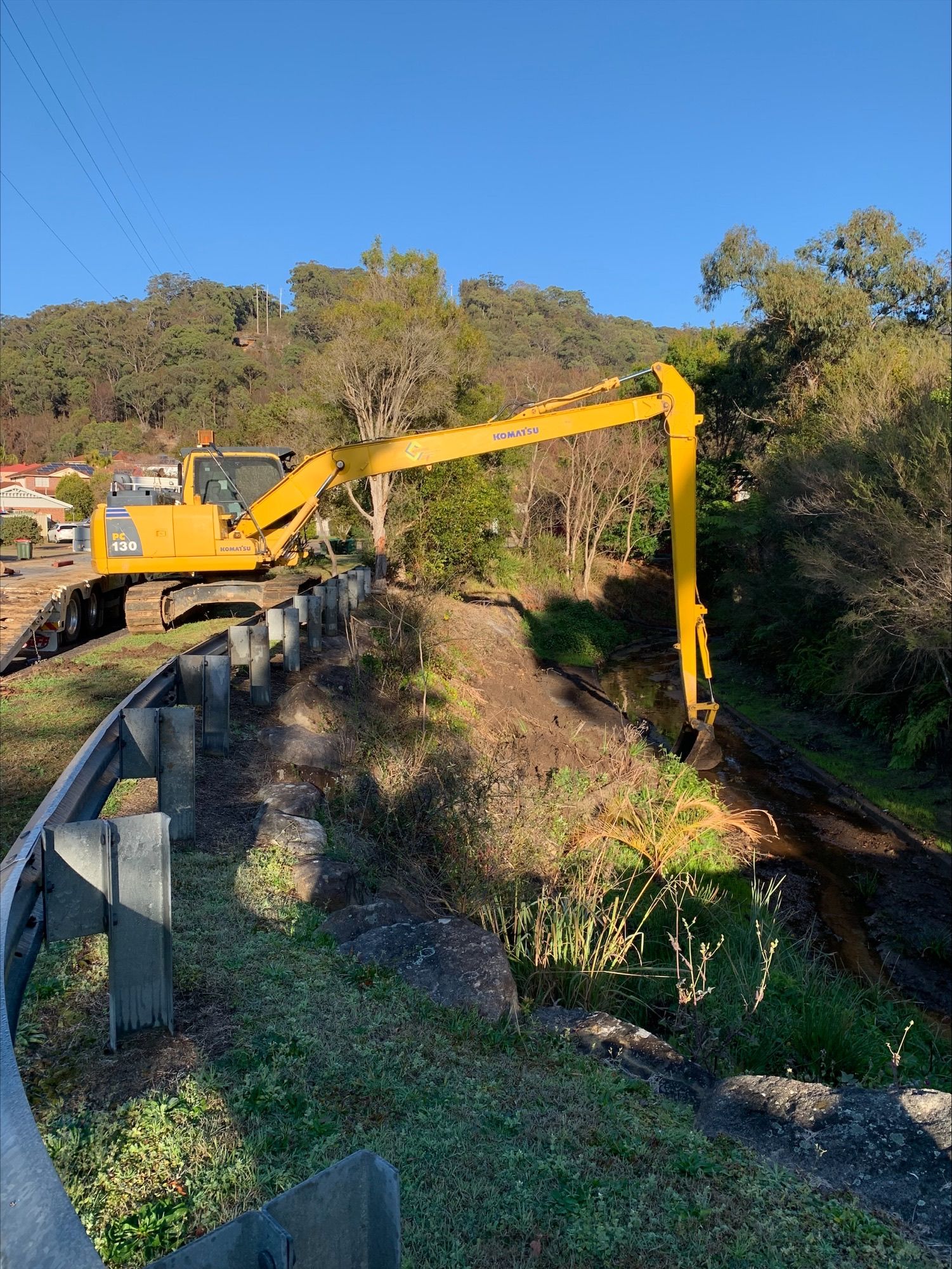 A yellow excavator is working on a railroad track. — Adam Lowe Earthmoving Pty Ltd in Somersby, NSW