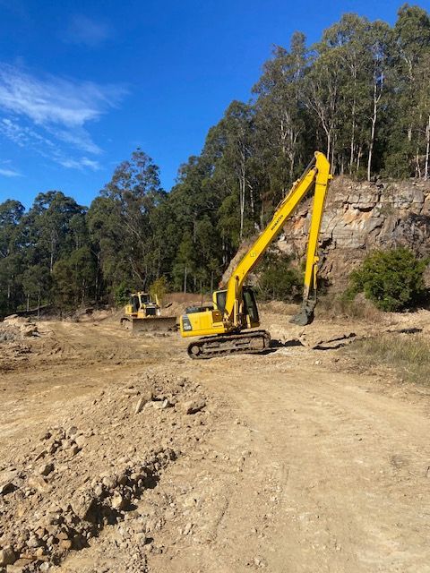 A Yellow Dump Truck Is Parked on A Sandy Beach — Adam Lowe Earthmoving Pty Ltd in Somersby, NSW