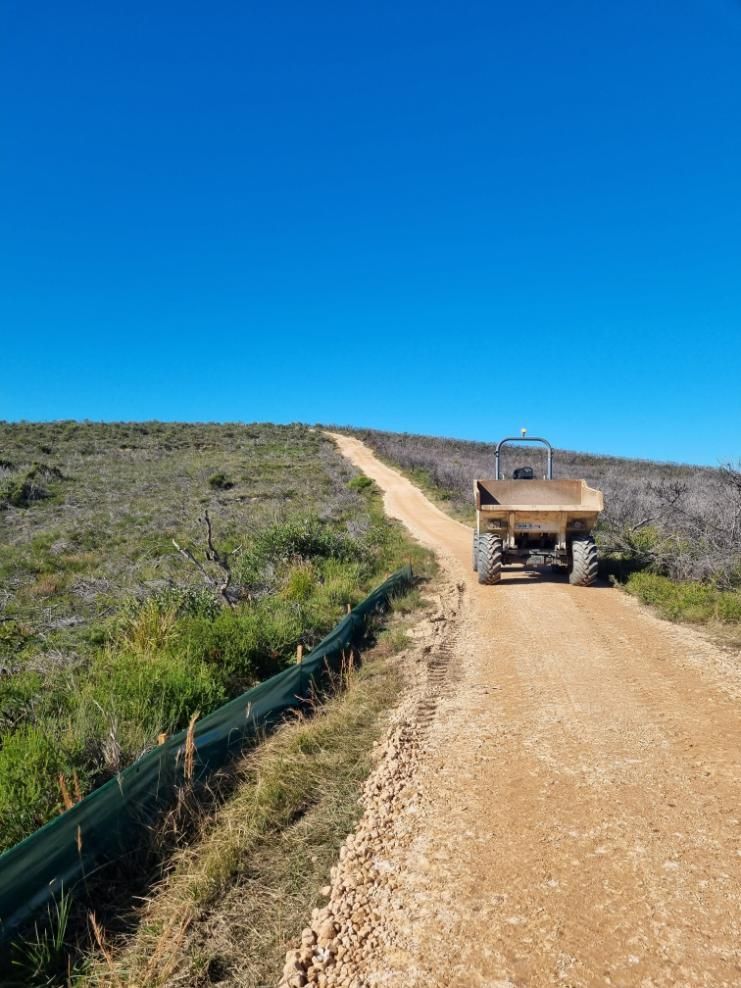 A Dump Truck Is Driving Down a Dirt Road — Adam Lowe Earthmoving Pty Ltd in Somersby, NSW