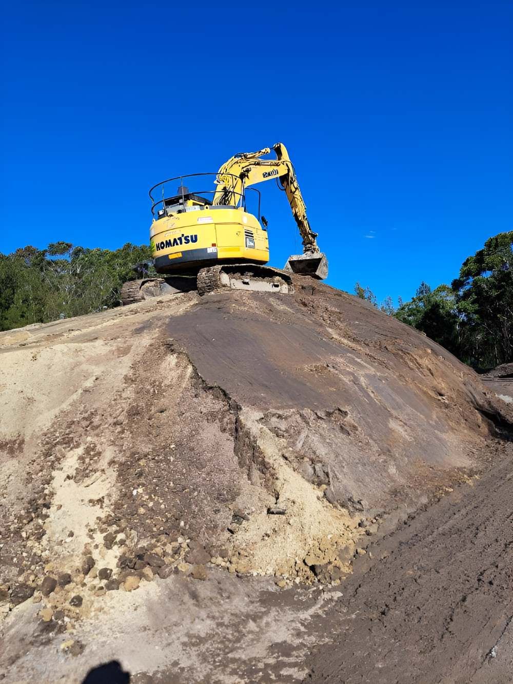 A Yellow Excavator Is Sitting on Top of A Pile of Dirt — Adam Lowe Earthmoving Pty Ltd in Somersby, NSW