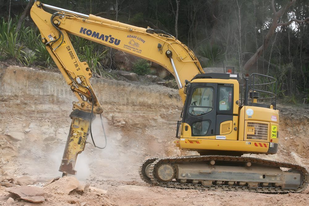 A Yellow Excavator Is Sitting on Top of A Dirt Field — Adam Lowe Earthmoving Pty Ltd in Somersby, NSW