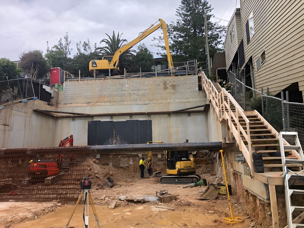 A Construction Site with A Yellow Excavator and Stairs — Adam Lowe Earthmoving Pty Ltd in Somersby, NSW