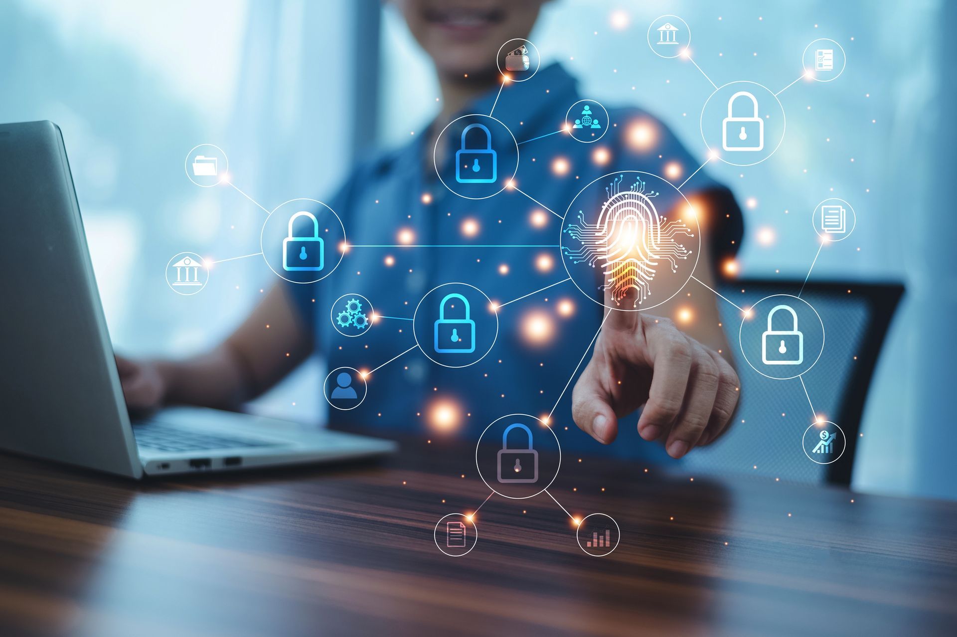 Persona que usa una computadora portátil, tocando una huella digital brillante, rodeada de íconos de seguridad digital.