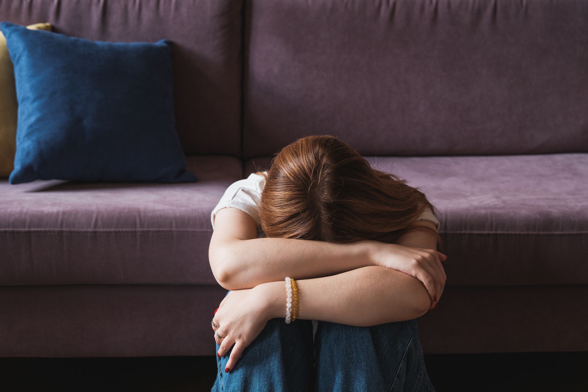 A woman is sitting on the floor with her head down