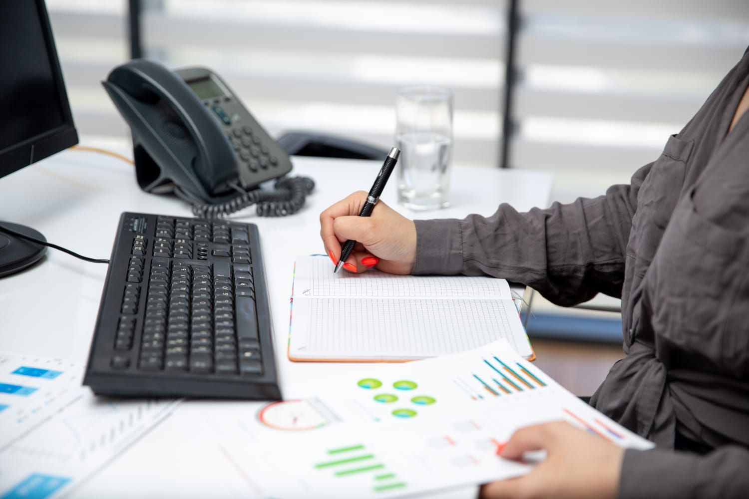 A woman is sitting at a desk writing in a notebook.