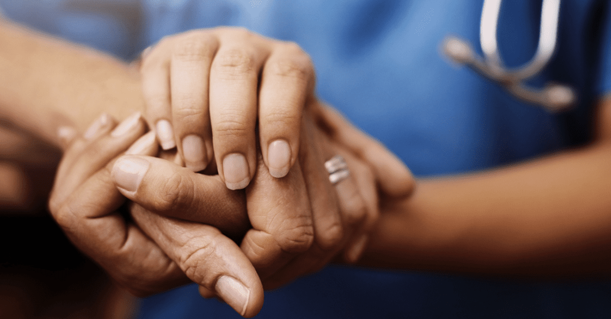 A nurse is holding the hand of a patient.