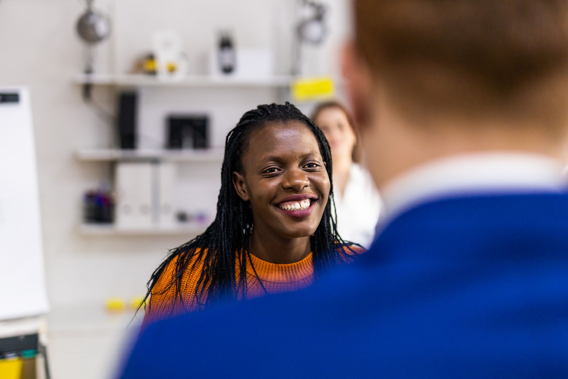 A woman is smiling while talking to a man in a blue shirt.